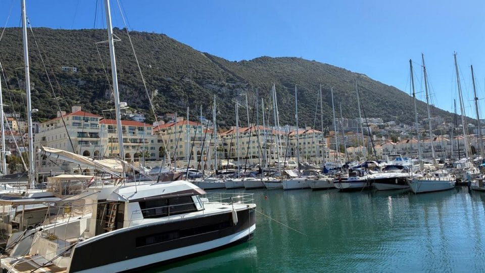 Queensway Quay Luxury Apartment and Marina Queensway Quay Marina in Gibraltar with luxury yachts, waterfront apartments, and views of the Rock under a clear blue sky.