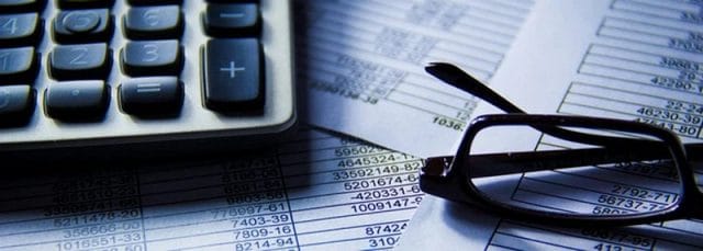 Gibraltar Tax Planning and Financial Assessment Calculator, financial documents and reading glasses representing tax planning and financial requirements for Category 2 and HEPSS status in Gibraltar.